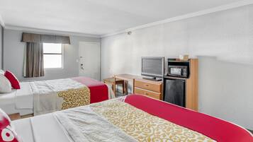A hotel room with two beds, a desk, a television, and a microwave.