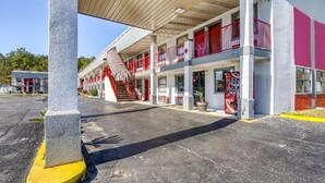 A motel with a two-story structure, a covered parking area, and a visible staircase leading to the entrance.