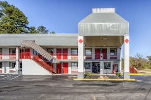 A motel with a central staircase, multiple balconies, and a covered front area. - Hotel Pineville LA Hwy 165 (Pineville)