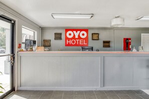 A reception desk with a 'OYO HOTEL' sign, a telephone, a fire alarm, and a small statue. - Hotel Pineville LA Hwy 165 (Pineville)