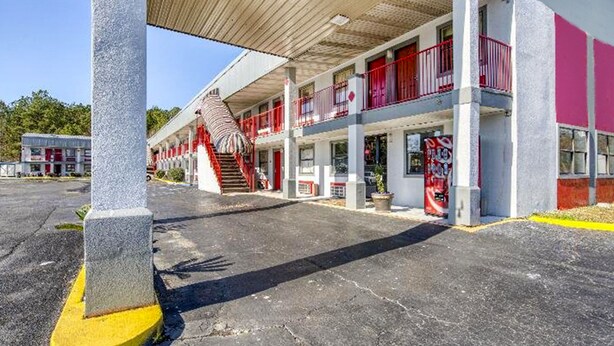 Ein Motel mit überdachtem Parkplatz, mehreren Balkonen und einer Treppe zum Eingang.