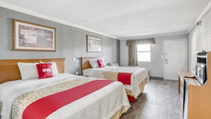Ein Hotelzimmer mit zwei Betten, einem Fernseher und einer Tür.