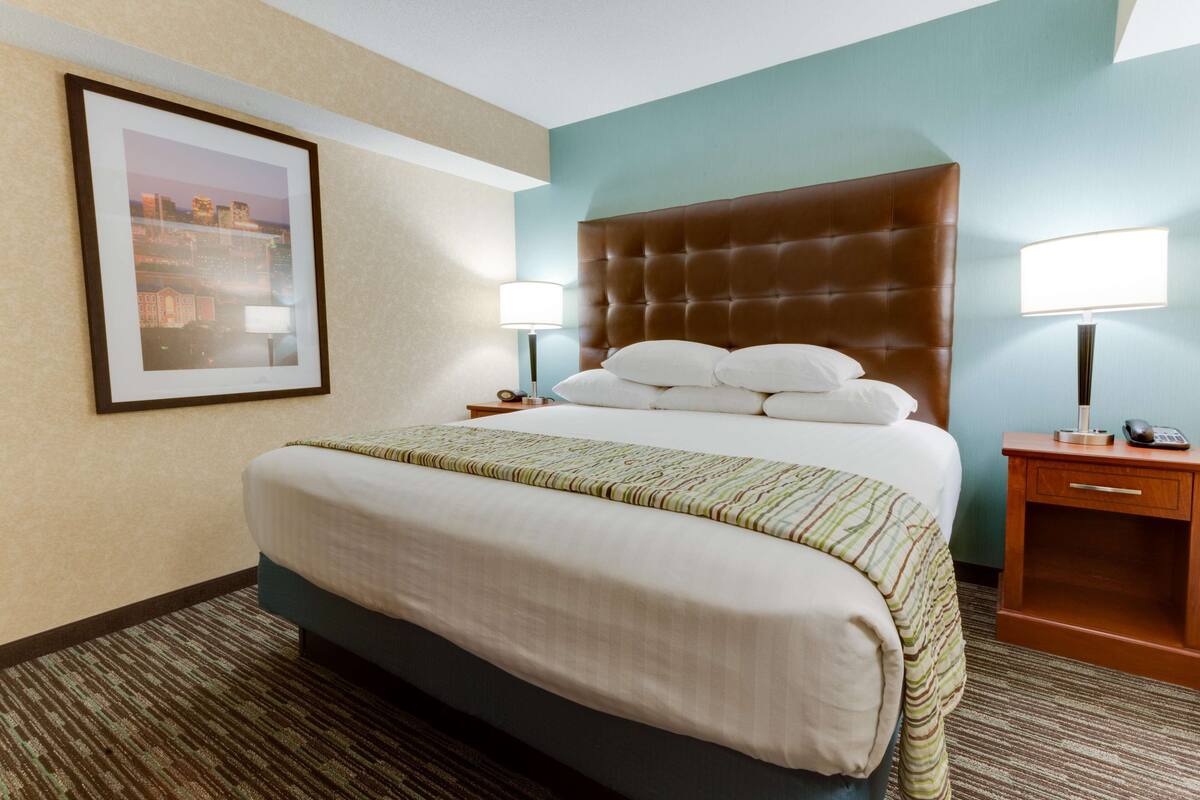A hotel room with a large bed, two bedside tables, and a framed picture on the wall.