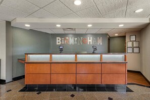 A reception desk with a 'BIRMINGHAM' sign above it, a glass partition, and framed certificates on the wall. - Drury Inn & Suites Birmingham Grandview (Birmingham)