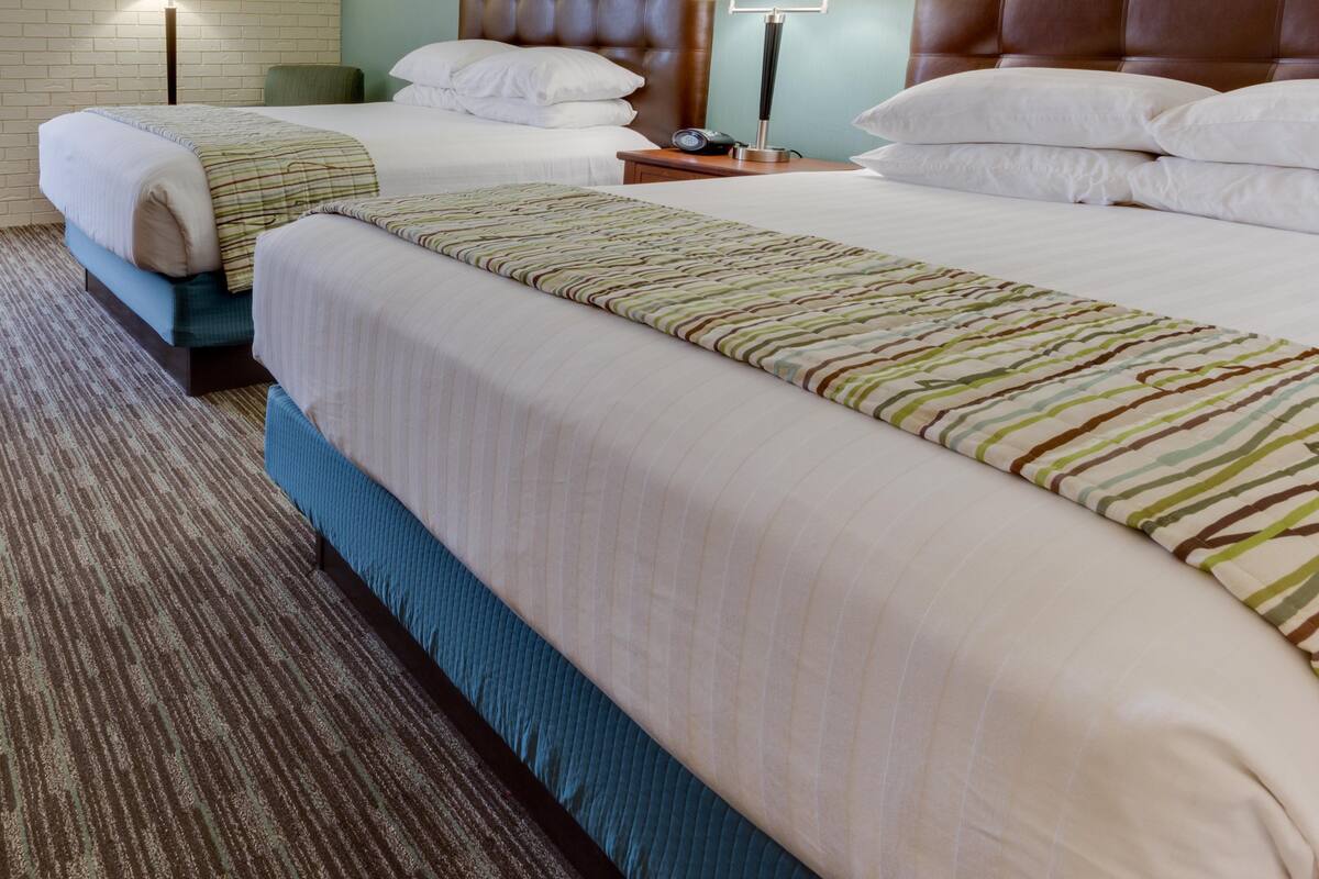 A hotel room with two beds, a brick wall, and a teal accent wall.