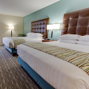 A hotel room with two beds, a brick wall, and a teal accent wall. - Drury Inn & Suites Birmingham Grandview (Birmingham)