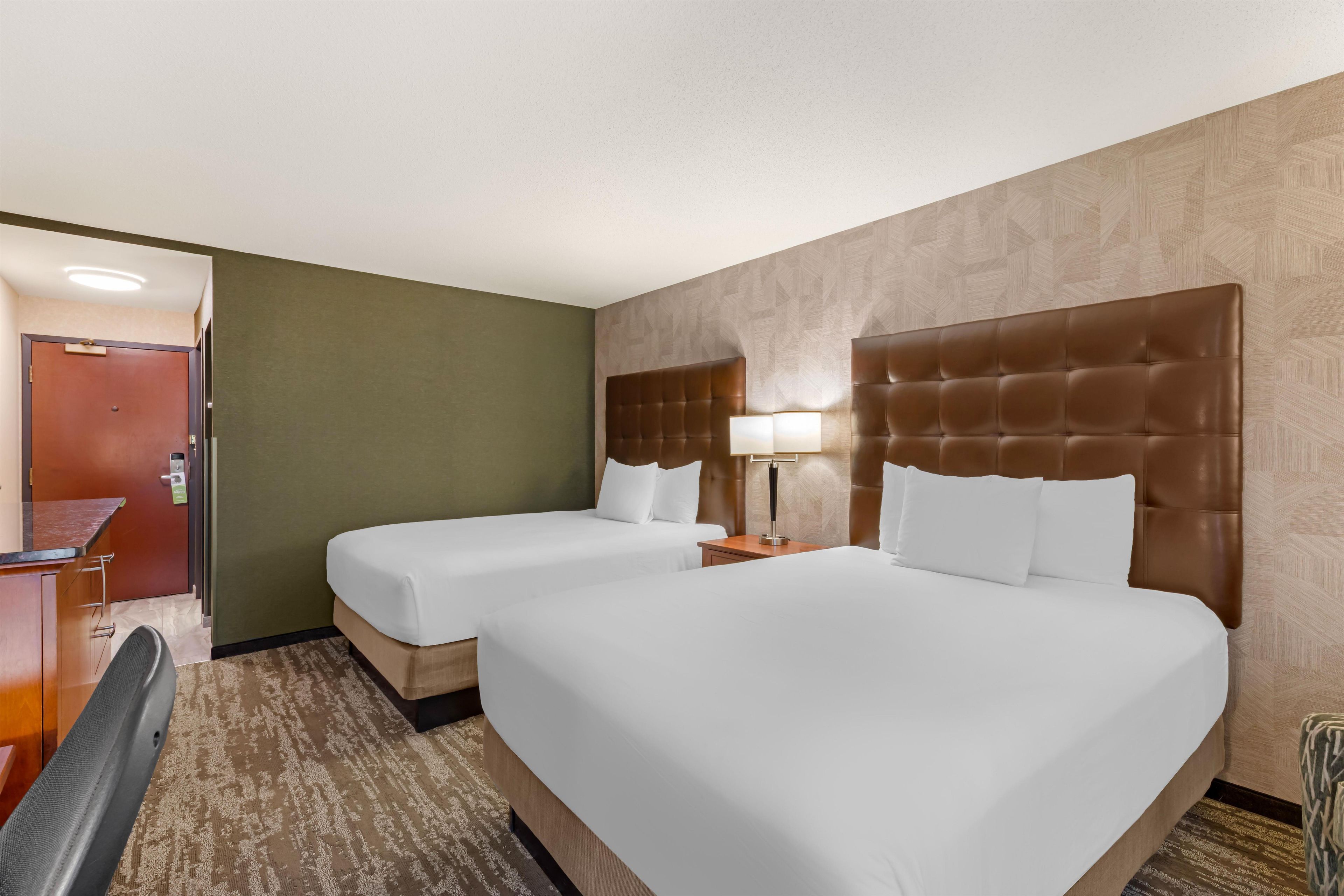 Une chambre d’hôtel avec deux lits, un bureau et une chaise.