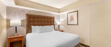 Habitación de hotel con una cama grande, dos mesitas de noche con lámparas, una mesita de noche de madera y un cuadro en la pared.