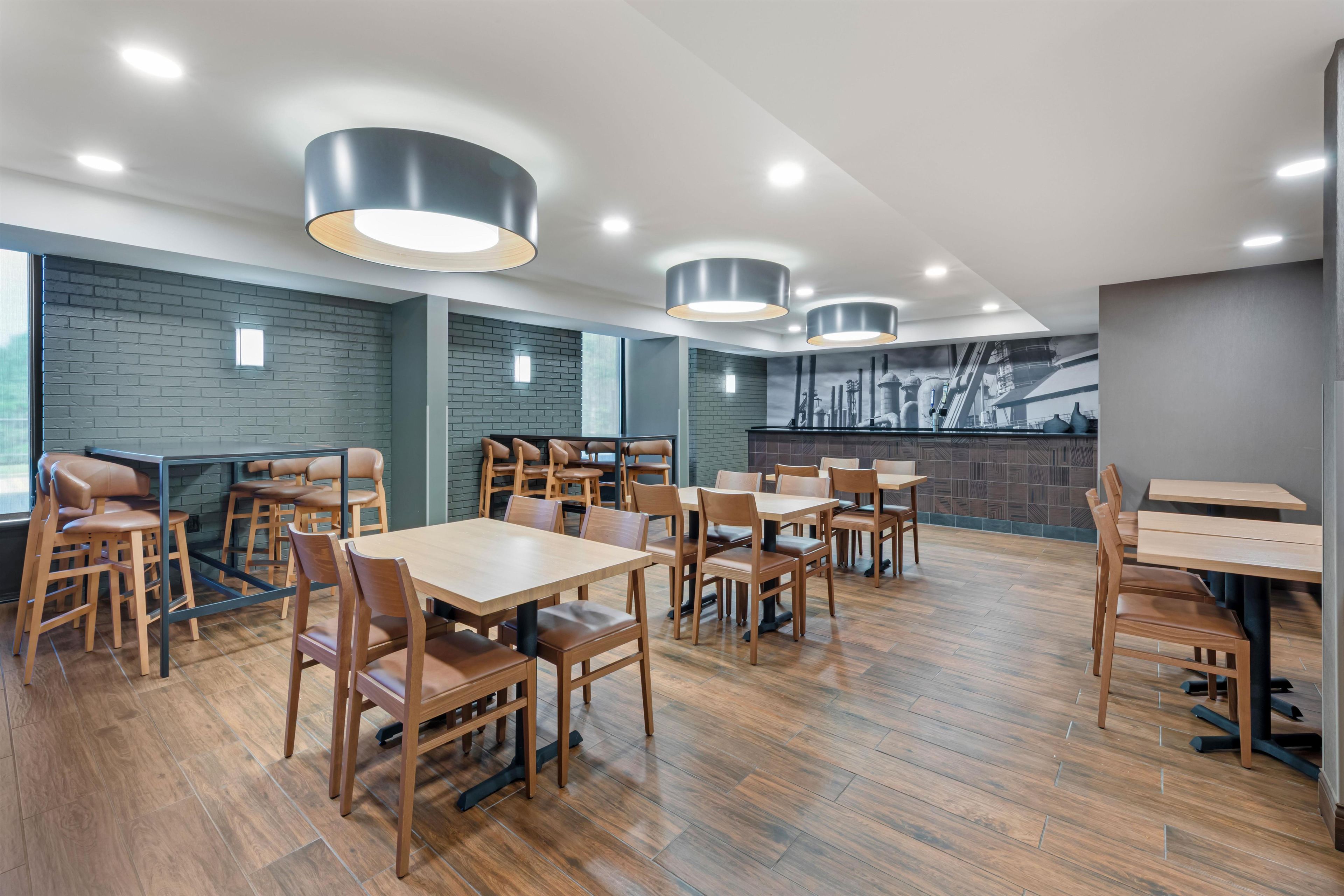Ein modernes Restaurant mit Holztischen und -stühlen, Ziegelwänden und Pendelleuchten.