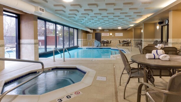 Una piscina interior con indicador de profundidad de 91 centímetros, junto a un área de descanso con mesas y sillas.
