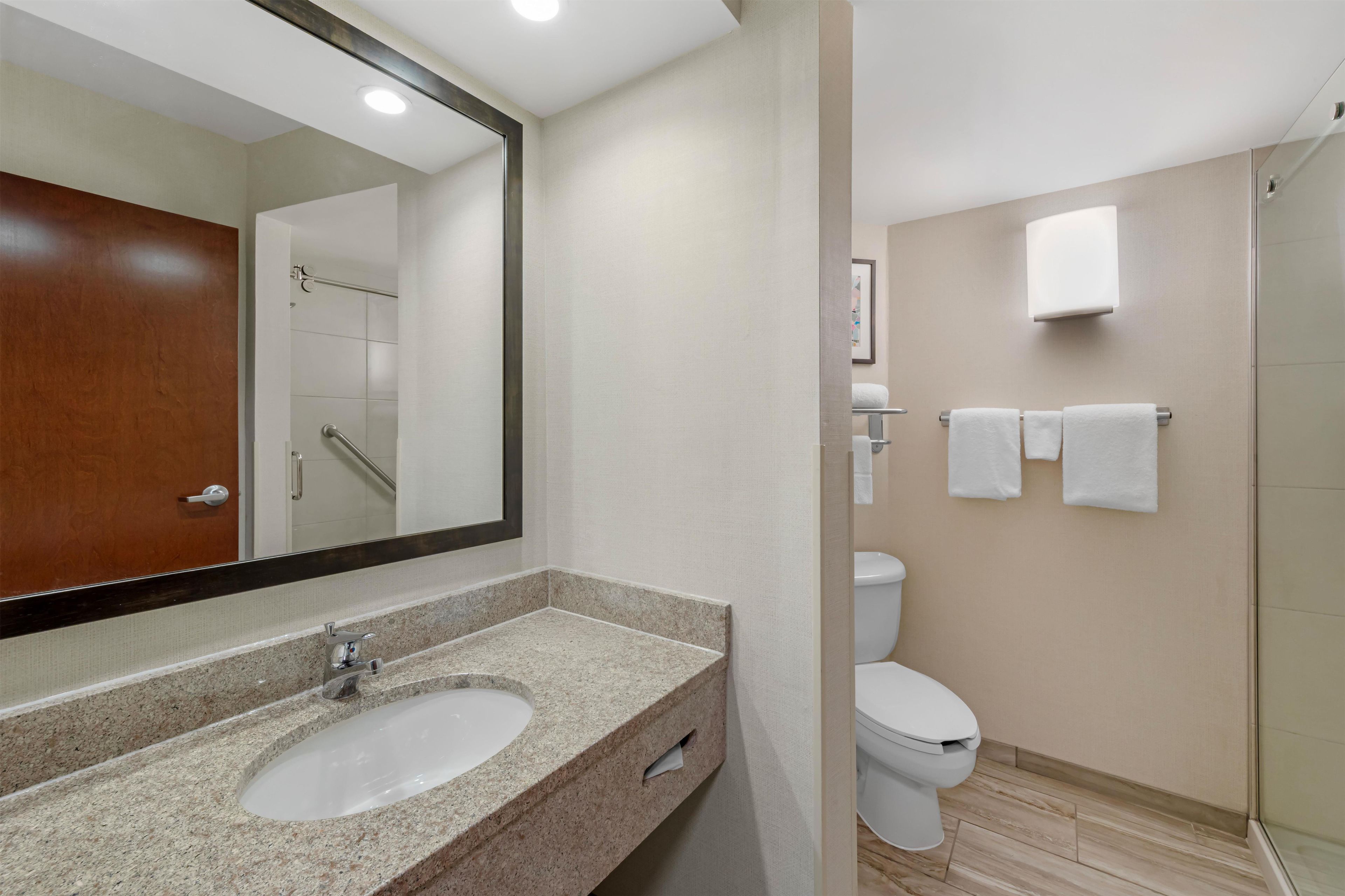 Une salle de bain équipée d’un lavabo, d’un miroir, de toilettes et d’un porte-serviettes.