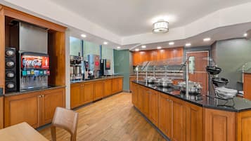 Una cocina moderna con armarios de madera, dispensador de Coca-Cola, cafetera y un espacio tipo bufé.
