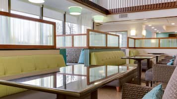 Un intérieur moderne avec des coins salon, des tables et un escalier.