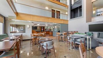A spacious indoor area with multiple seating arrangements, including tables and chairs, and a kitchen area in the background.