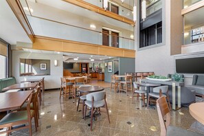 A spacious indoor area with multiple seating arrangements, including tables and chairs, and a kitchen area in the background. - Drury Inn & Suites Birmingham Grandview (Birmingham)