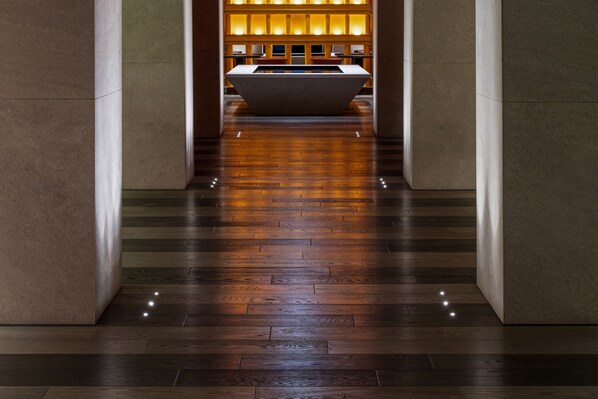 A corridor with a wooden floor leading to a reception area with a reception desk and a seating area. - HOTEL IL PALAZZO (Fukuoka)