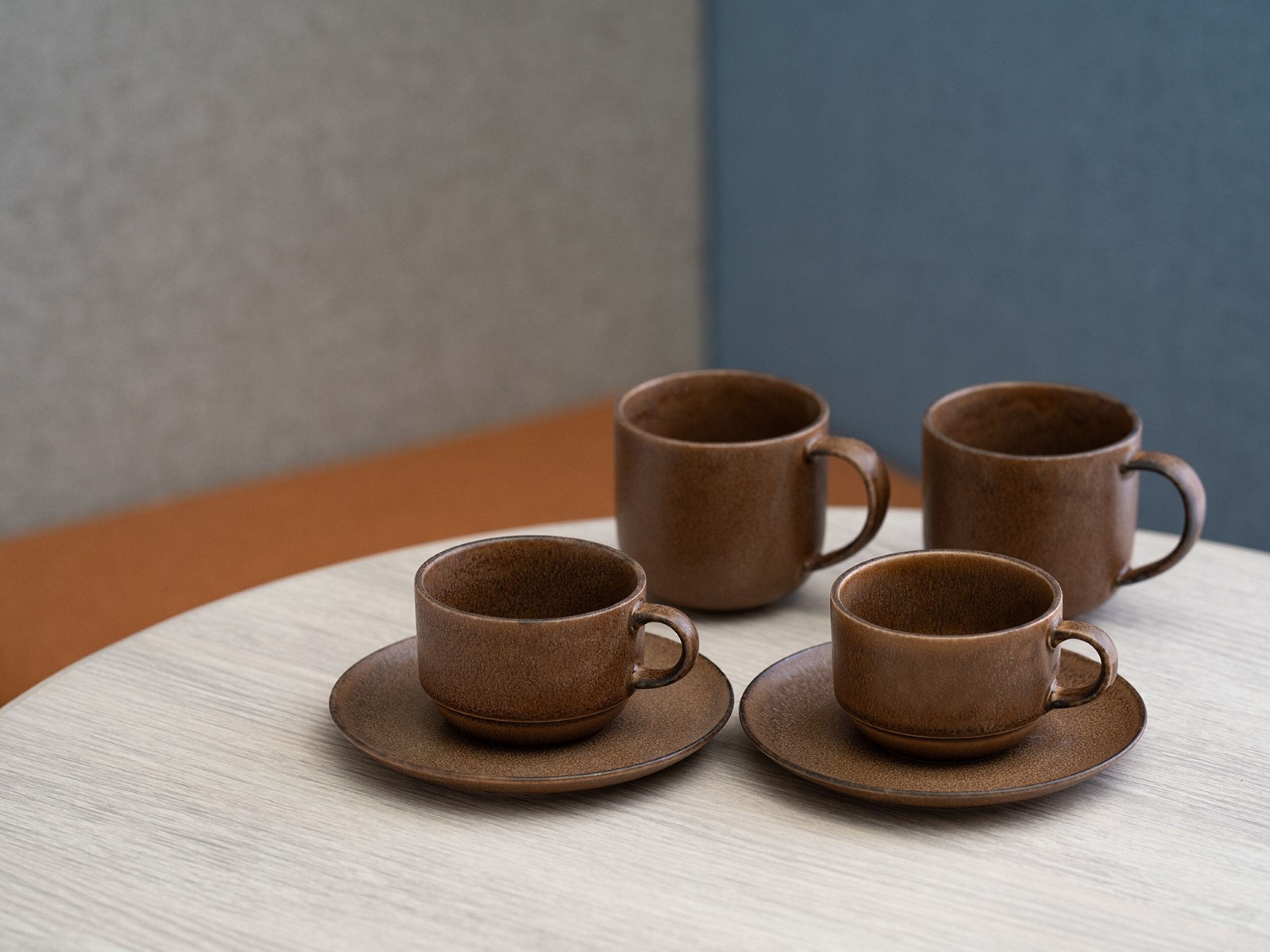 A table with four ceramic cups and saucers.