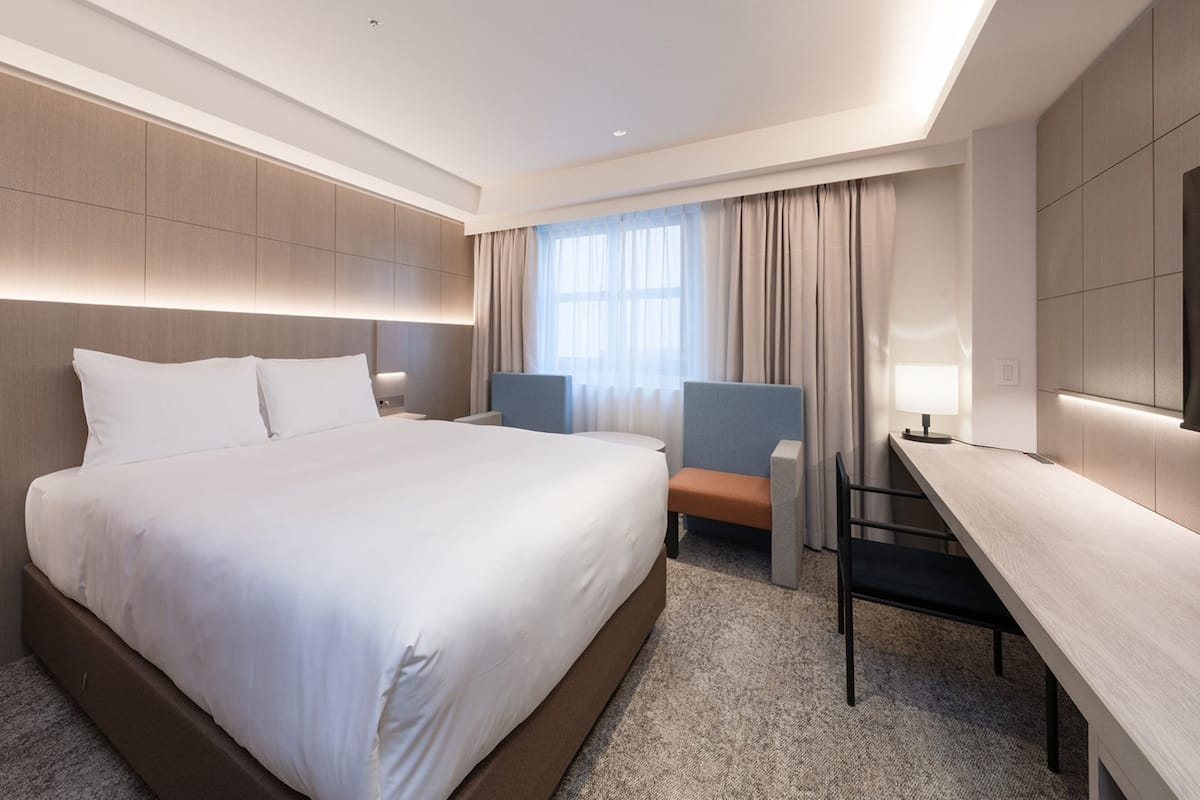 Een moderne hotelkamer met een groot bed, een bureau en een stoel.