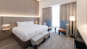 Una habitación de hotel moderna con una cama grande, un escritorio, una silla y una pequeña mesa.