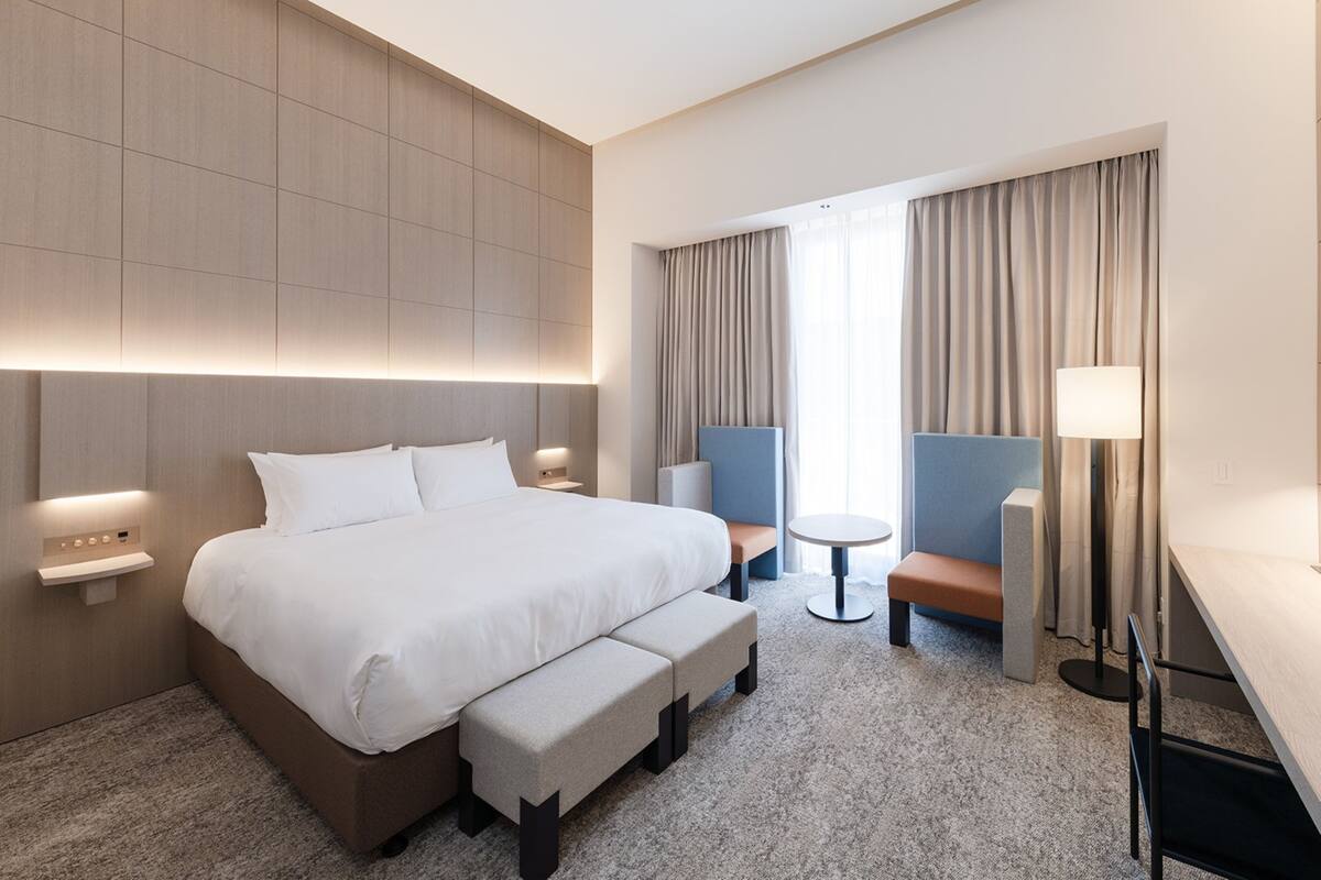 Een moderne hotelkamer met een groot bed, een bureau, een stoel en een klein tafeltje.