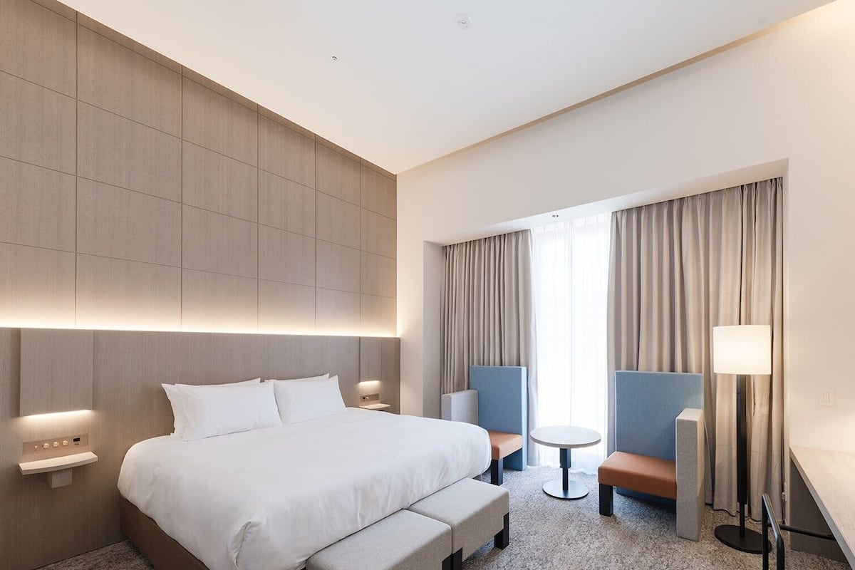 Een moderne hotelkamer met een groot bed, een bureau, een stoel, een klein tafeltje en een televisie.