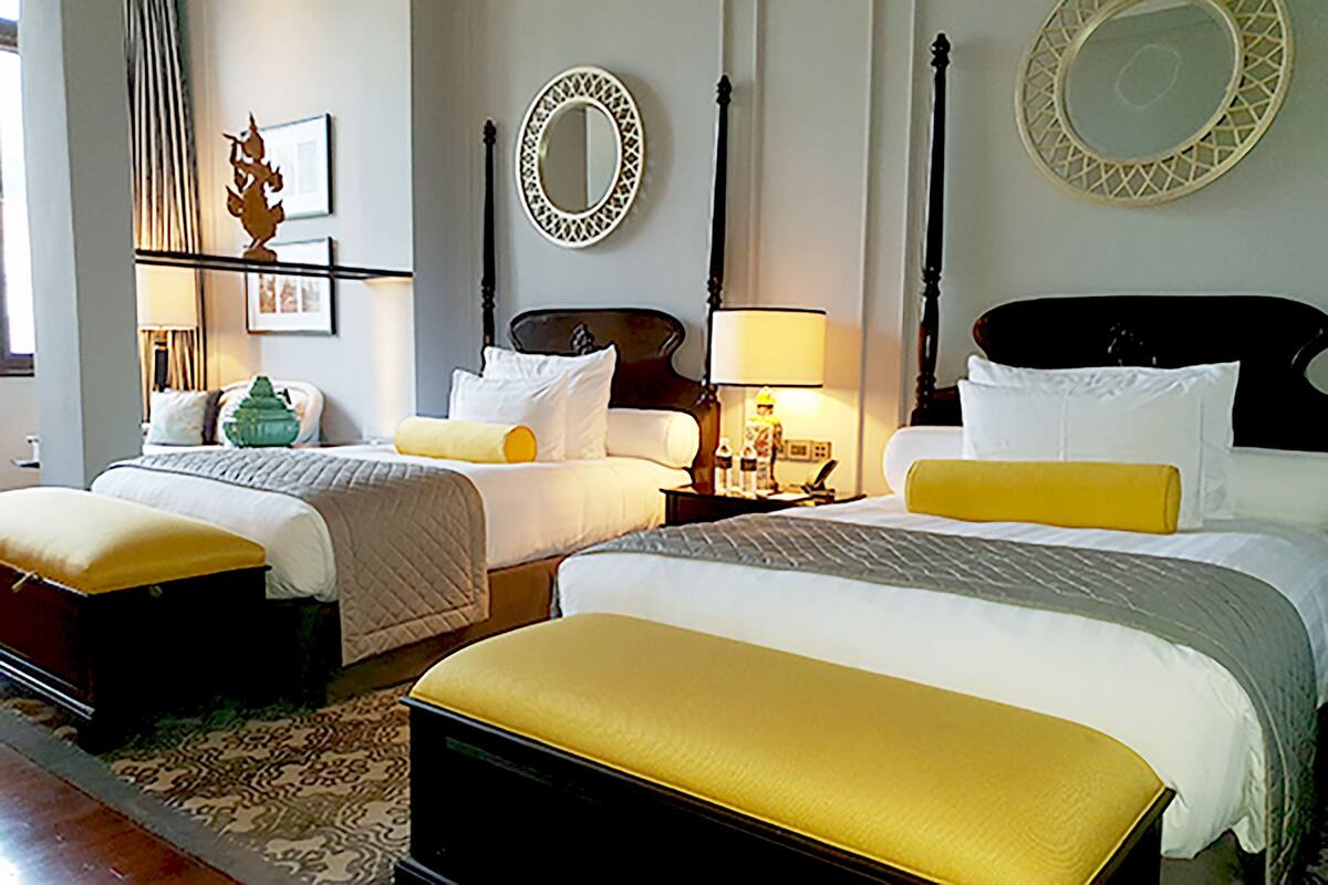 A hotel room with two beds, a large mirror, and a nightstand with a lamp.