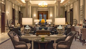 A hotel lobby with a central seating area, two lamps, a chandelier, and a decorative book on a table. - The Strand Yangon (Yangon)