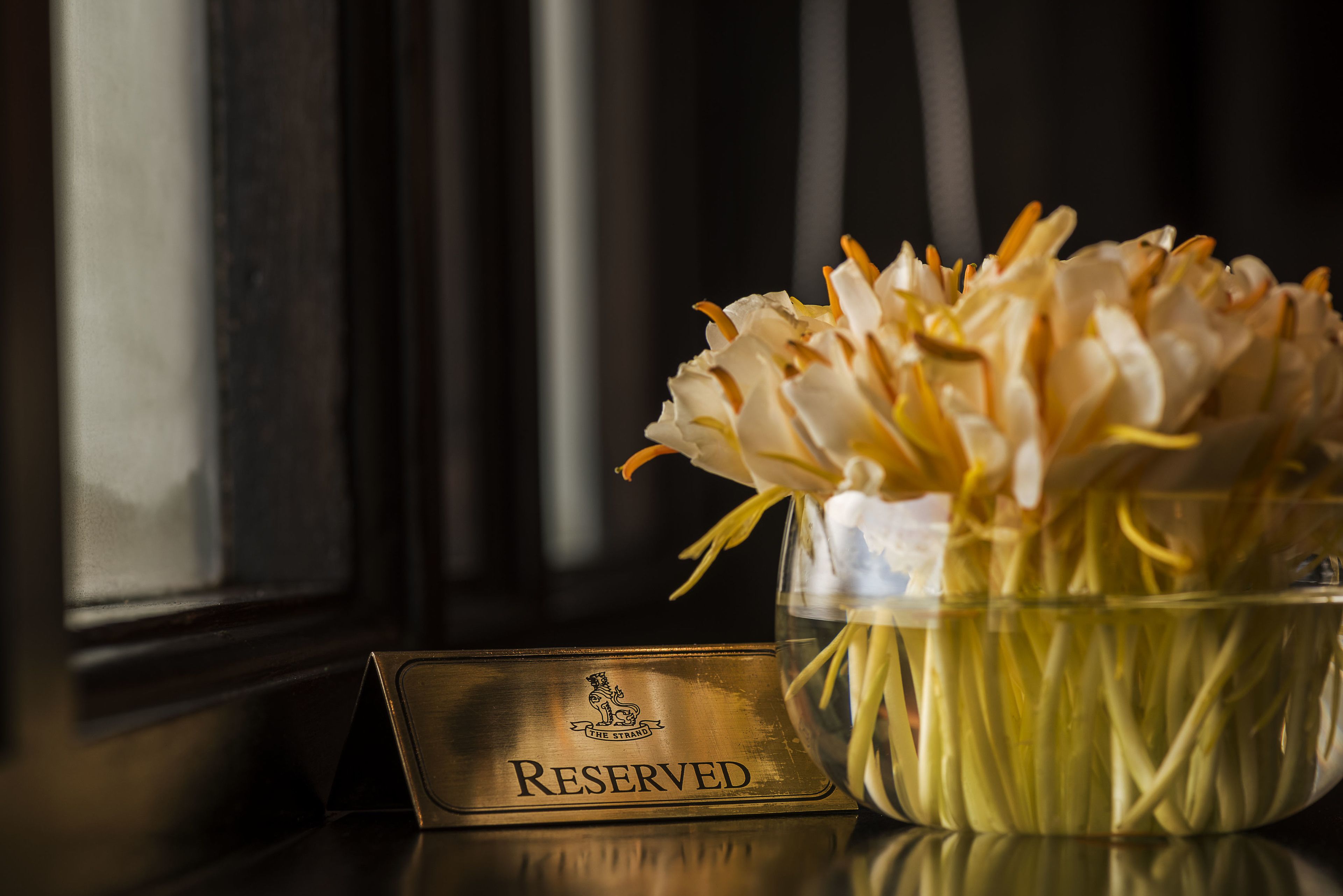 A reserved sign with a floral arrangement in a glass vase.