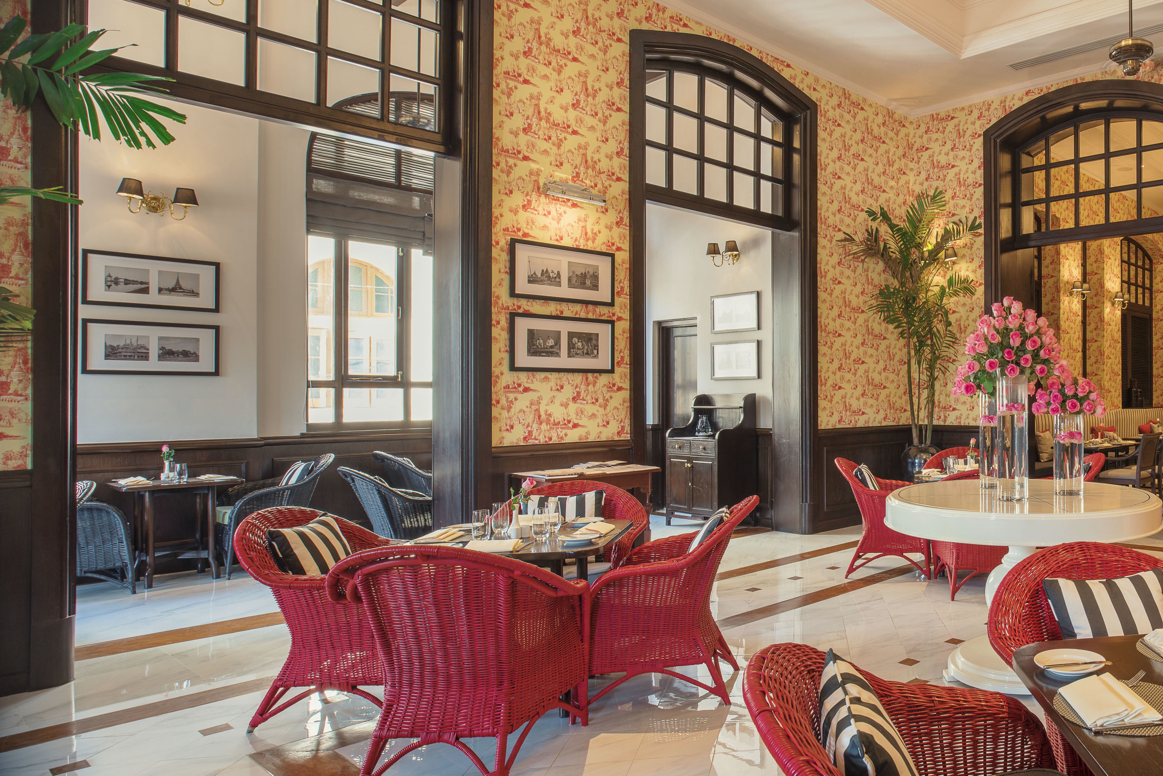 Un vestíbulo de hotel con muebles de mimbre rojo, cuadros enmarcados en las paredes y un ventanal grande.