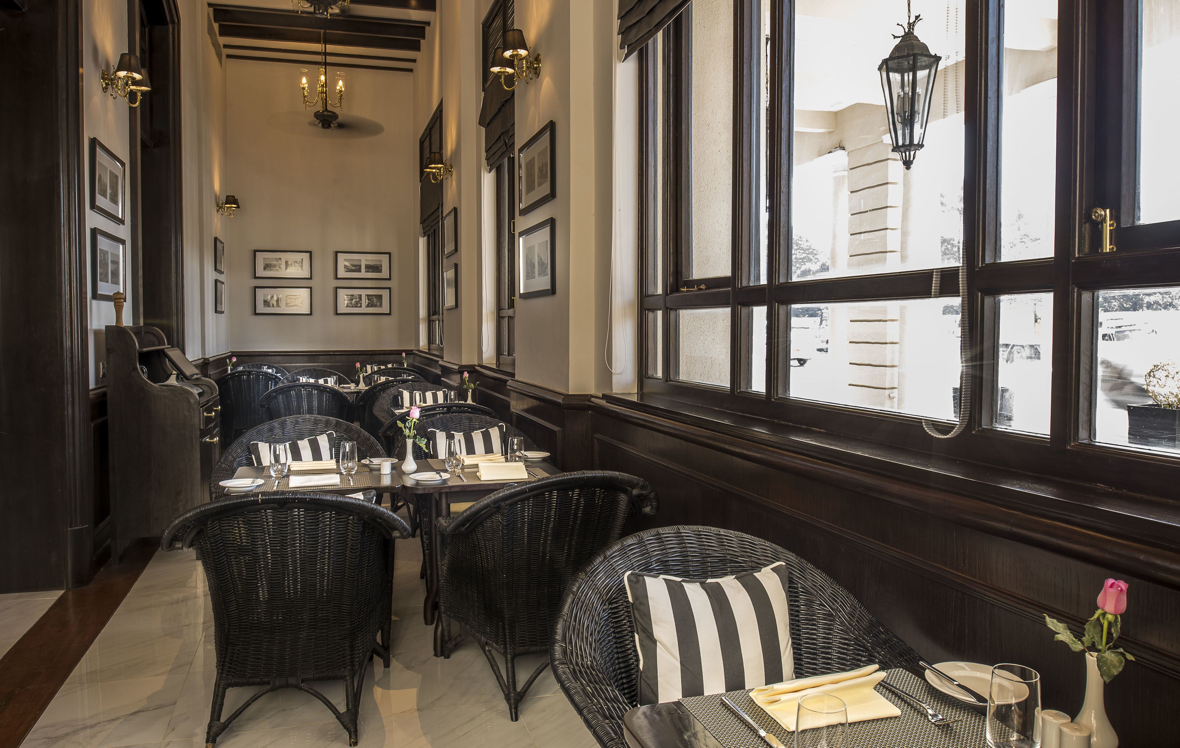 Un restaurante con paneles de madera oscura, mobiliario de mimbre y ventanas amplias con vistas a la ciudad.