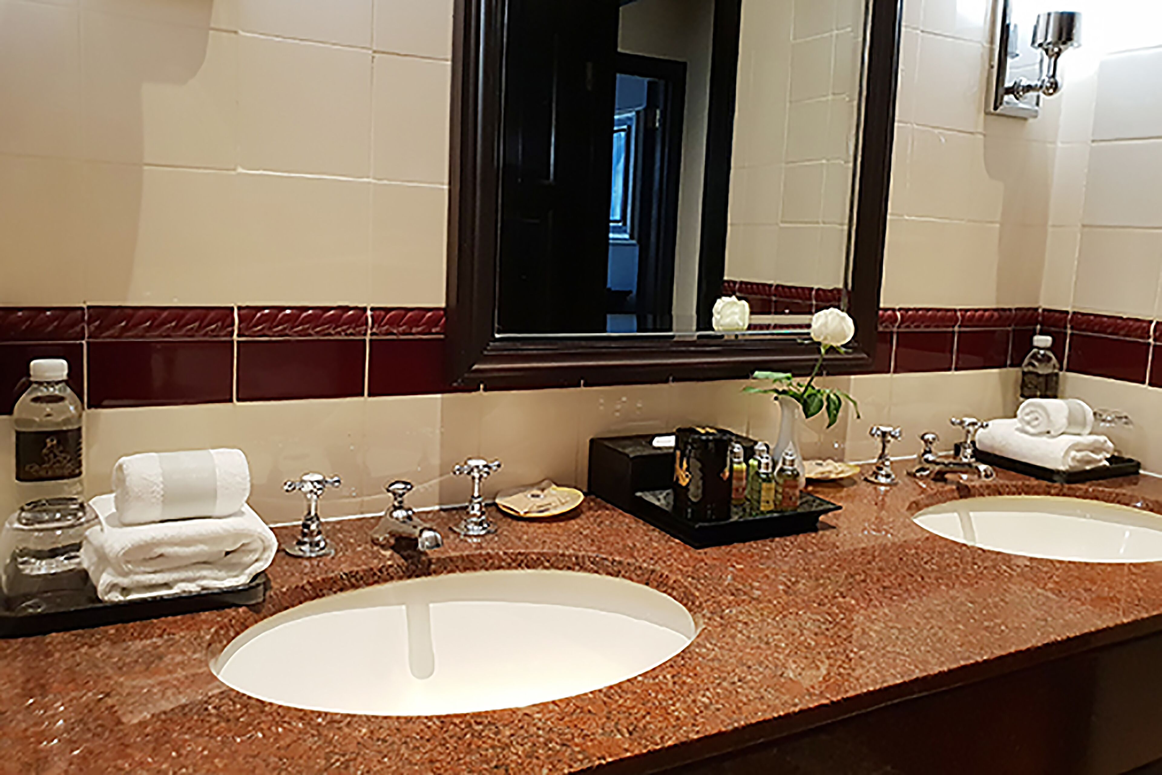 A bathroom with two sinks, a mirror, and a vanity with toiletries.