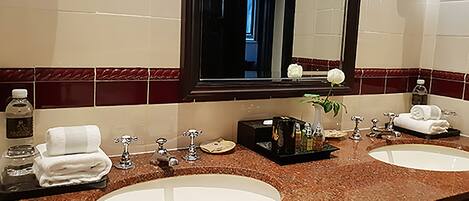 A bathroom with two sinks, a mirror, and a vanity with toiletries.