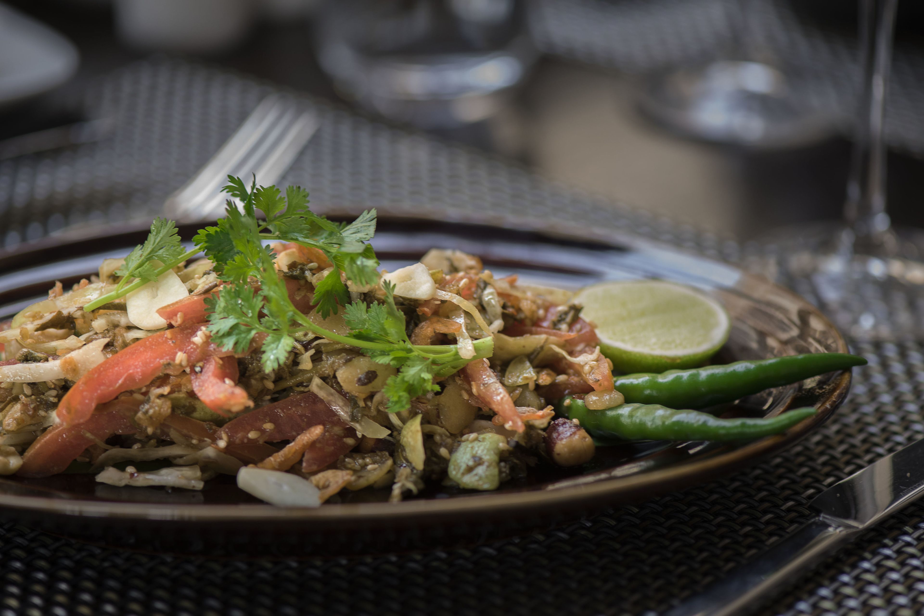 A plate of food with various ingredients, garnished with herbs and a lime wedge.