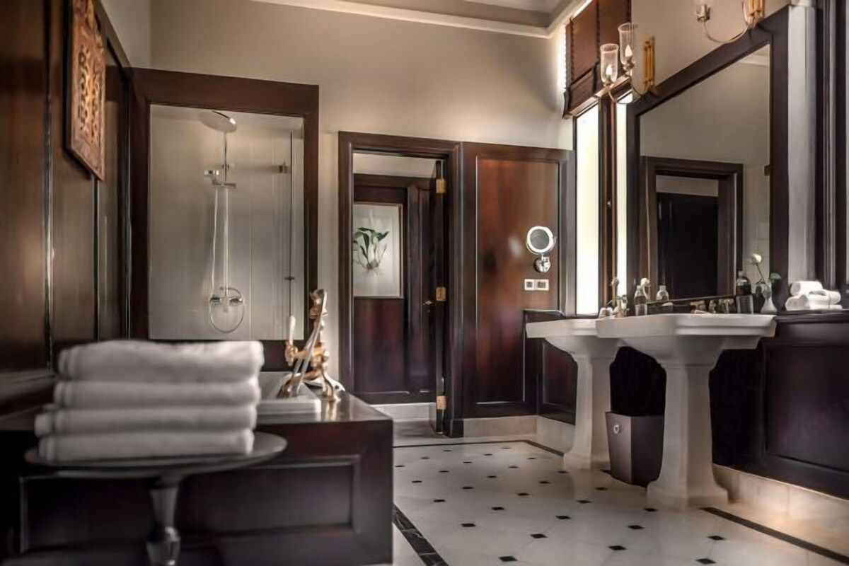 A modern bathroom with a large mirror, a shower, and a sink.