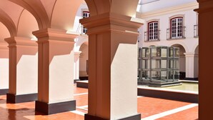 A covered courtyard with columns, a fountain, and a building with large windows. - Pousada Castelo de Alcácer do Sal - Historic Hotel (Alcacer do Sal)
