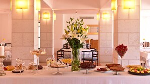 A buffet table with various desserts and a vase of flowers in the center. - Pousada Castelo de Alcácer do Sal - Historic Hotel (Alcacer do Sal)