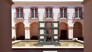 A courtyard with a central glass structure, arched walkways, and a tiled floor. - Pousada Castelo de Alcácer do Sal - Historic Hotel (Alcacer do Sal)