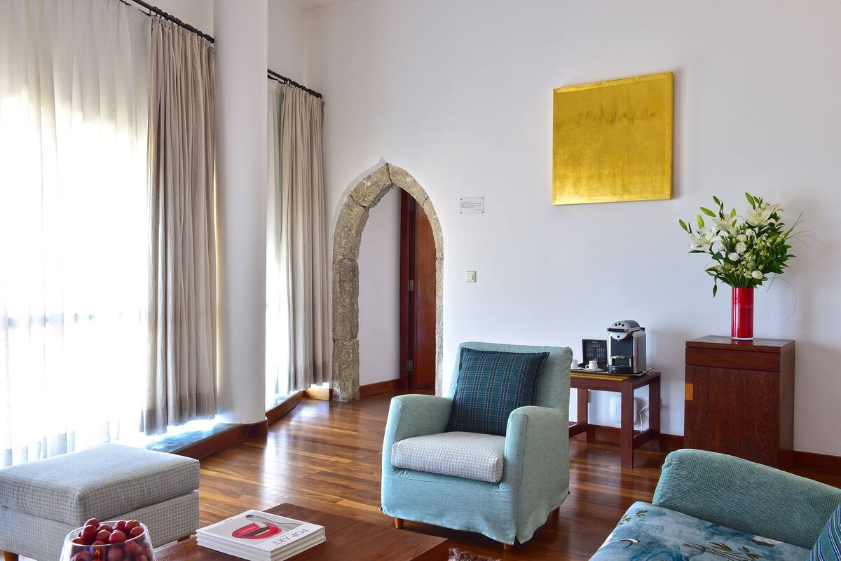 A living room with a stone archway, a coffee machine, and a vase of flowers.