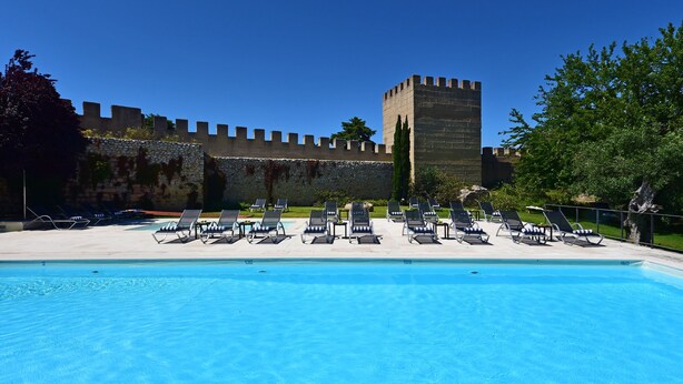 A swimming pool with lounge chairs and a castle-like structure in the background. - Pousada Castelo de Alcácer do Sal - Historic Hotel (Alcacer do Sal)
