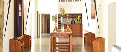 A church interior with wooden pews, a central table, and a reception desk.