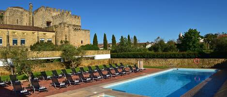 A swimming pool with lounge chairs and a castle in the background.