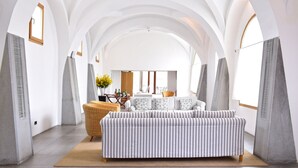 Un interior moderno con un sofá grande y a rayas, un sillón de mimbre y una mesa de comedor con sillas.