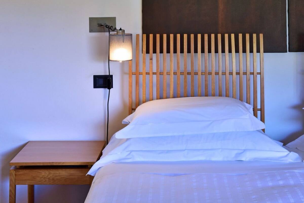 A bedroom with a wooden headboard, a bedside table, and a wall-mounted lamp.