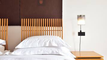 A neatly made bed with white linens, a wooden headboard, and a bedside table with a lamp.