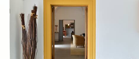 Un couloir avec une arche jaune qui mène à un espace de vie comprenant un canapé et un fauteuil.