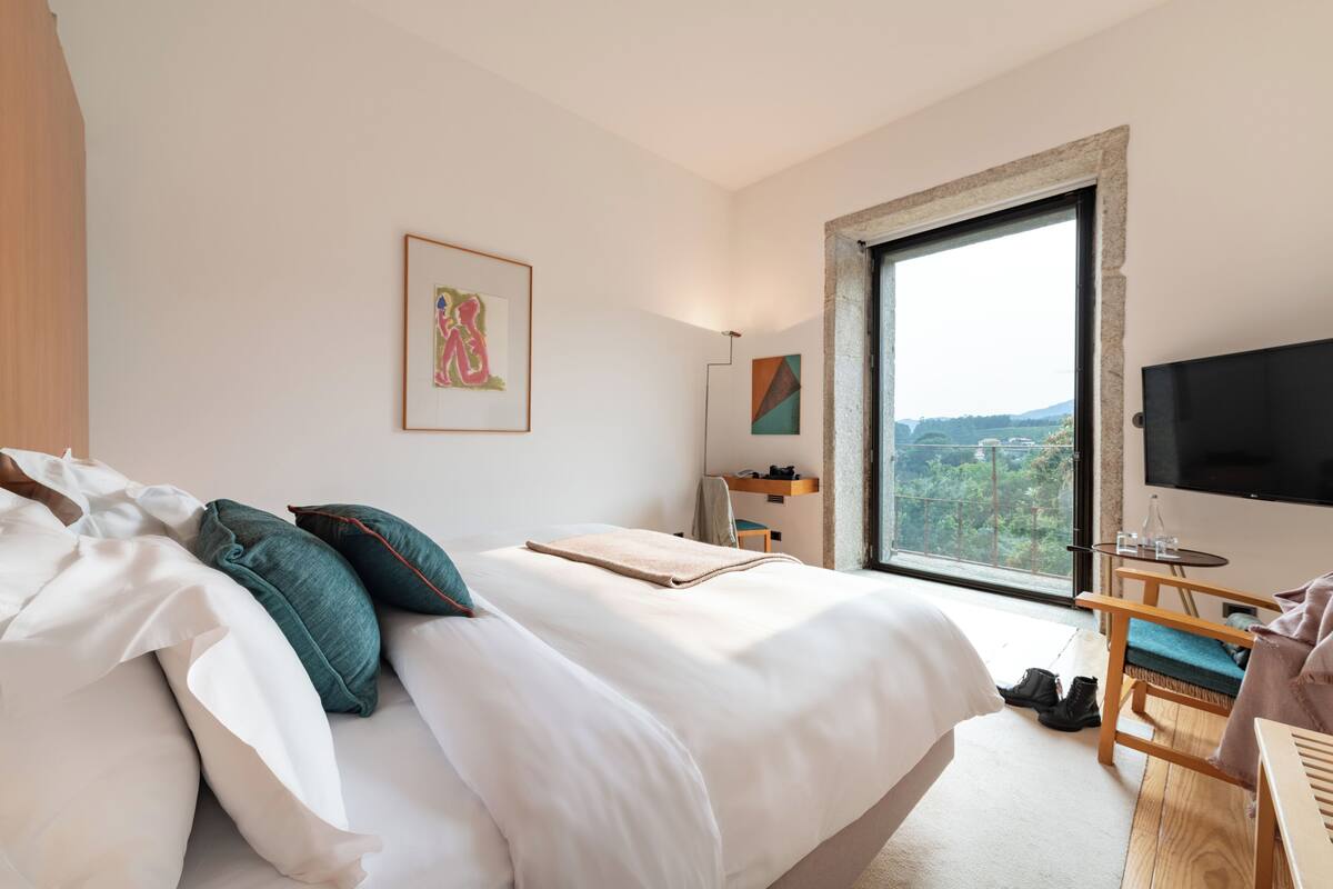 Una habitación de hotel moderna con una cama grande, un escritorio, una silla y un televisor.