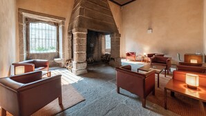 Una habitación acogedora con chimenea de piedra, sofás de cuero y un amplio ventanal.
