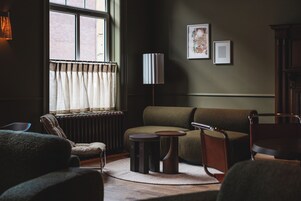 A living room with a sofa, armchairs, a table, a lamp, and a radiator.