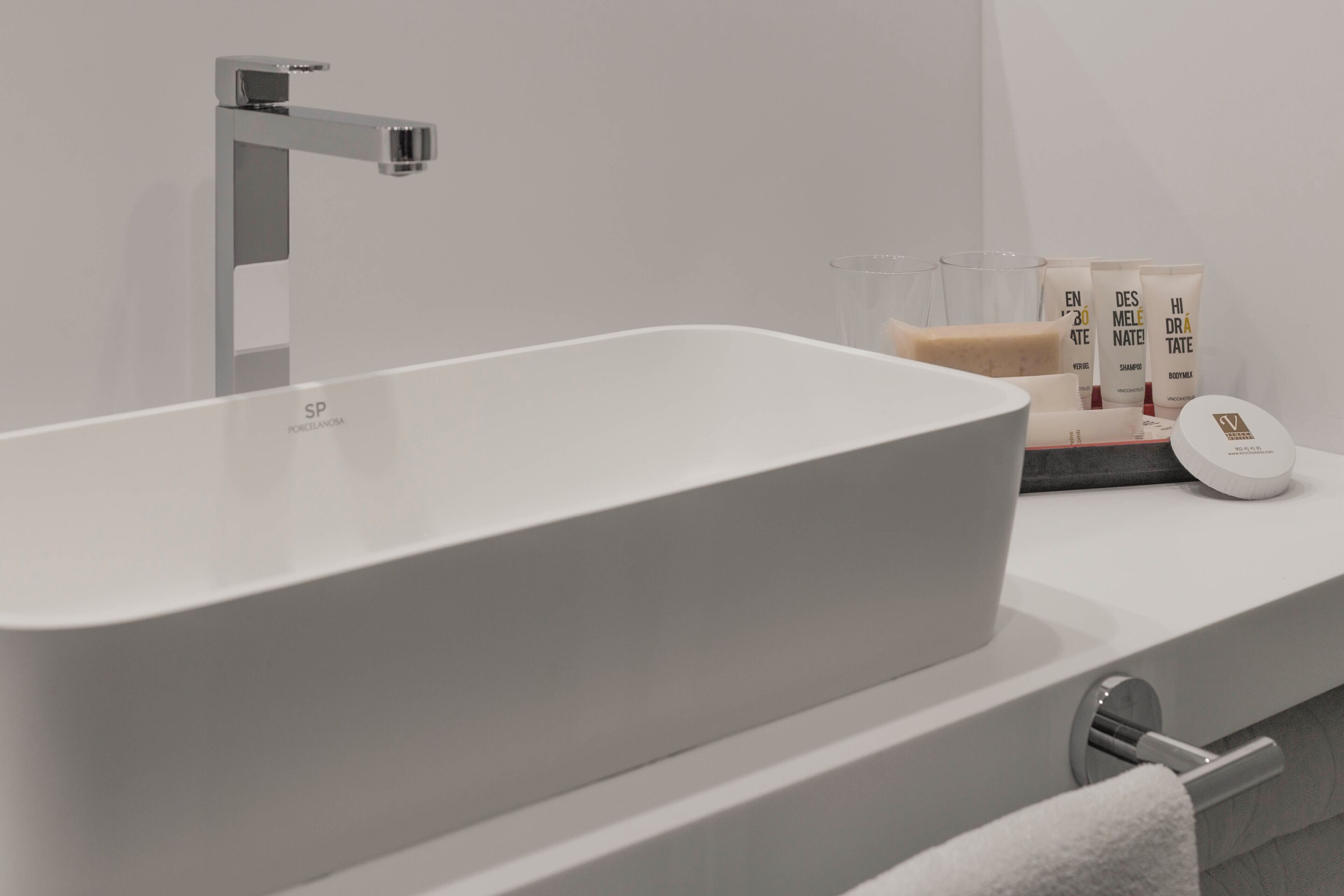 A modern bathroom with a large white bathtub, a chrome faucet, and a white countertop with toiletries.