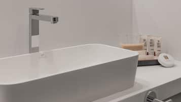A modern bathroom with a large white bathtub, a chrome faucet, and a white countertop with toiletries.